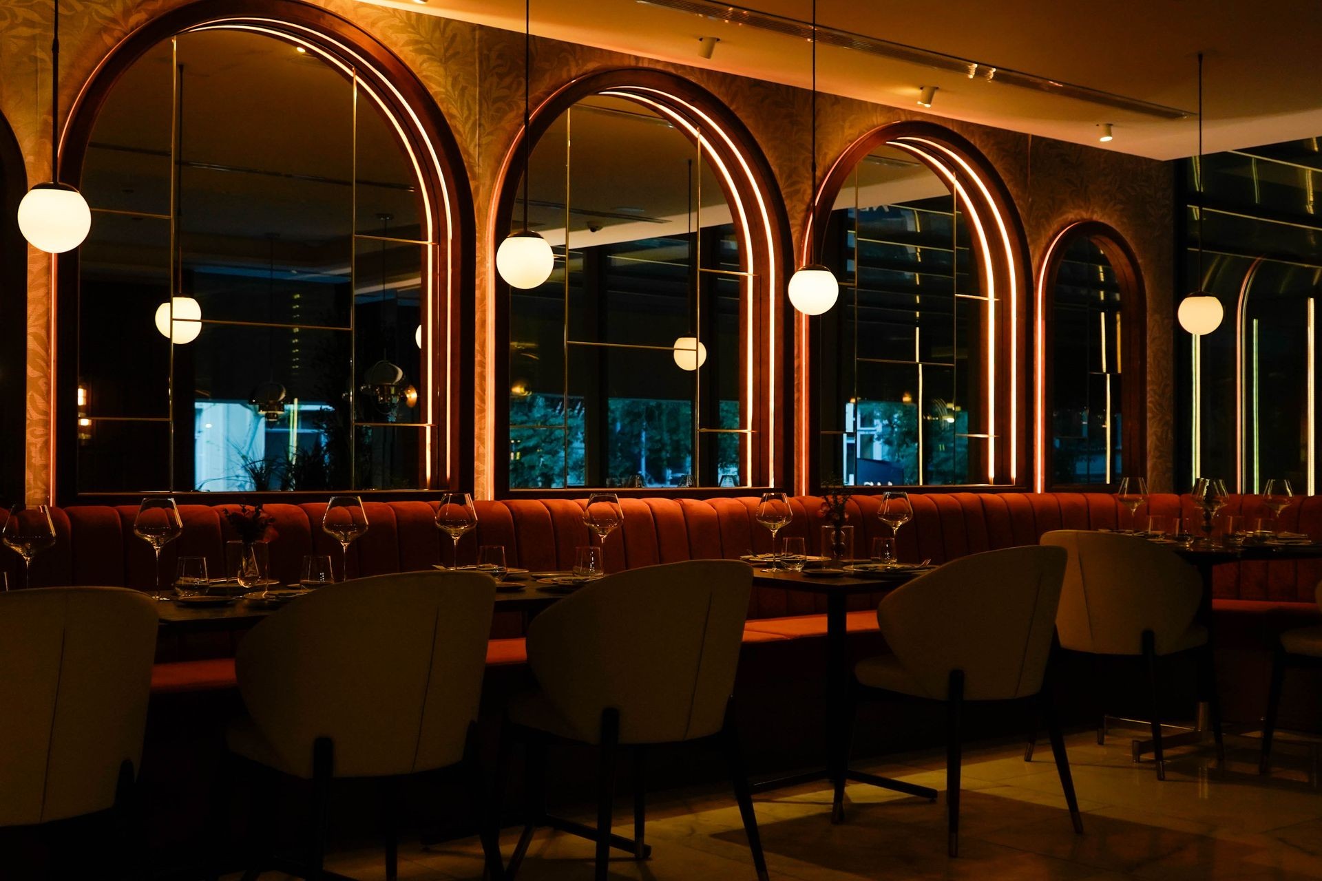 Elegant restaurant interior with arched mirrors, pendant lights, and tables set for dining.