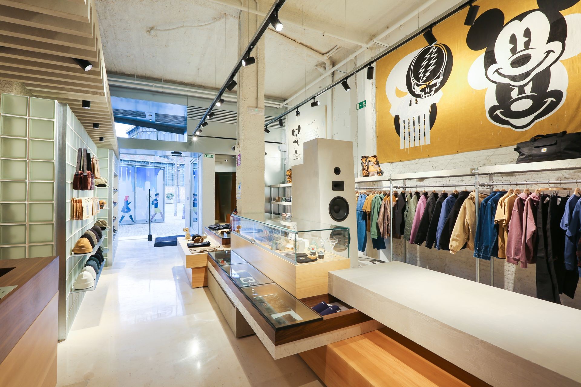 Modern clothing store interior with racks of colorful jackets and accessories displayed on shelves.
